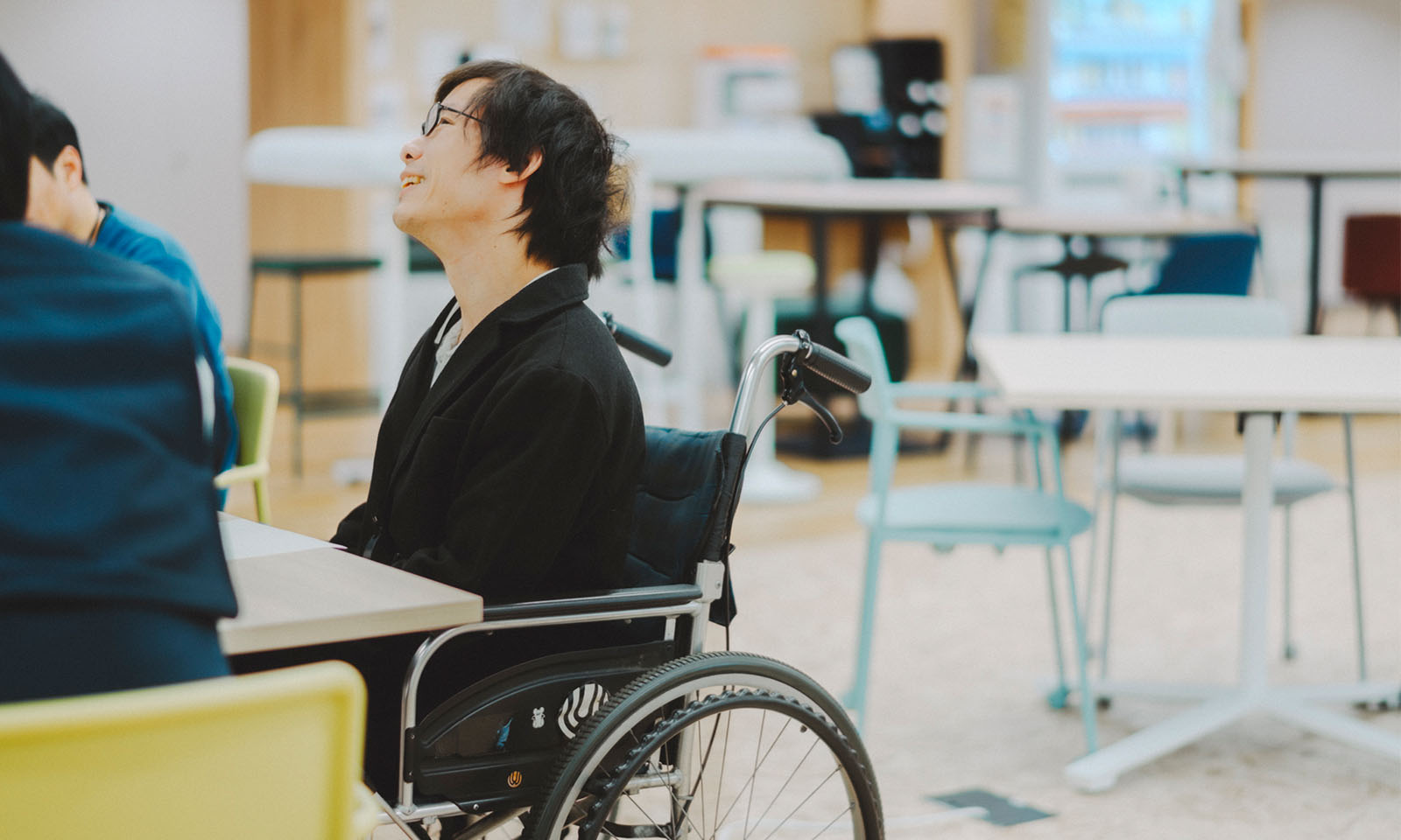 車椅子に座り、優しい笑顔で上を見上げながら、経験したことを思い出しながらインタビューで語る近藤さん