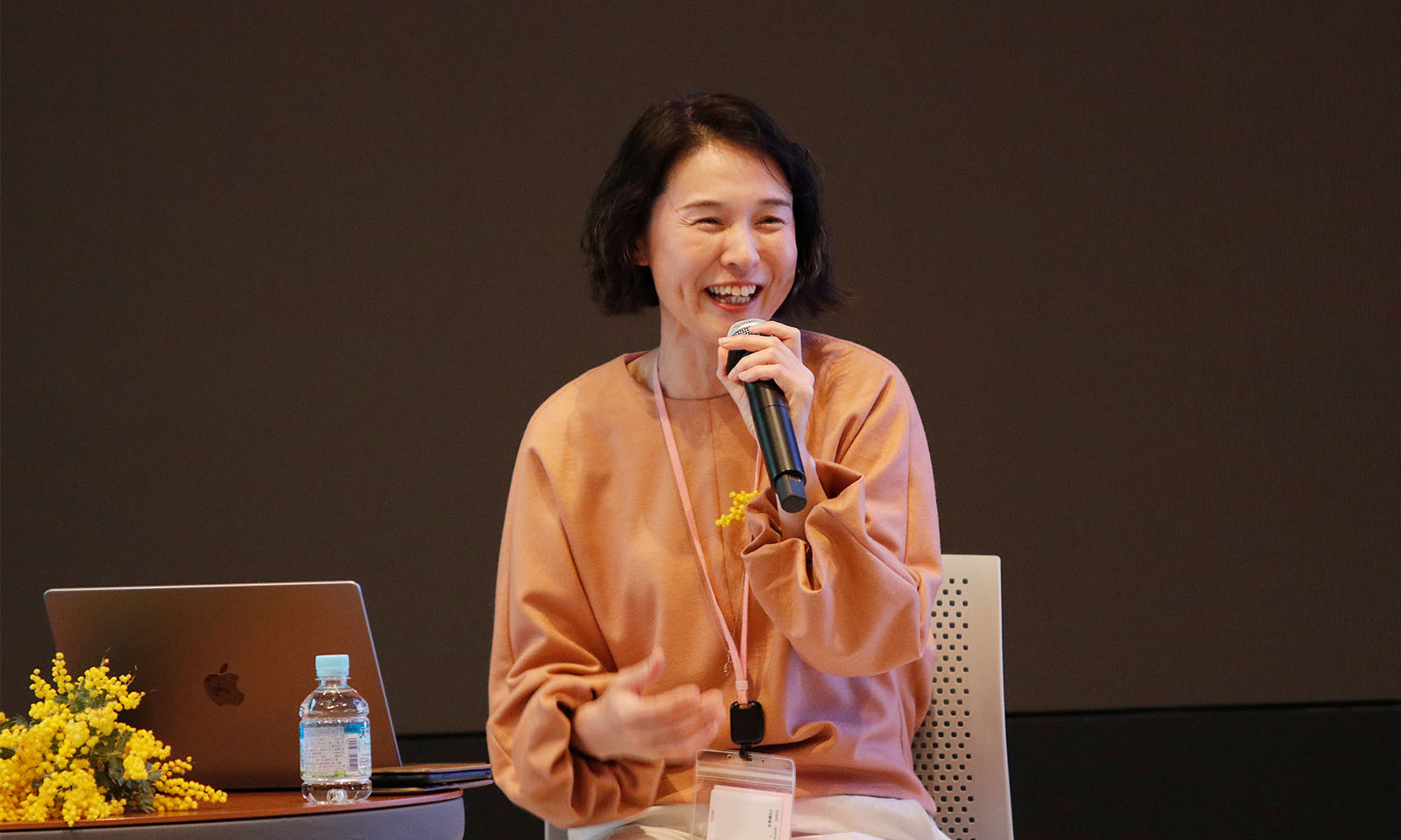 ステージ前方に座りマイクを持ちながら笑顔で話す西村さん