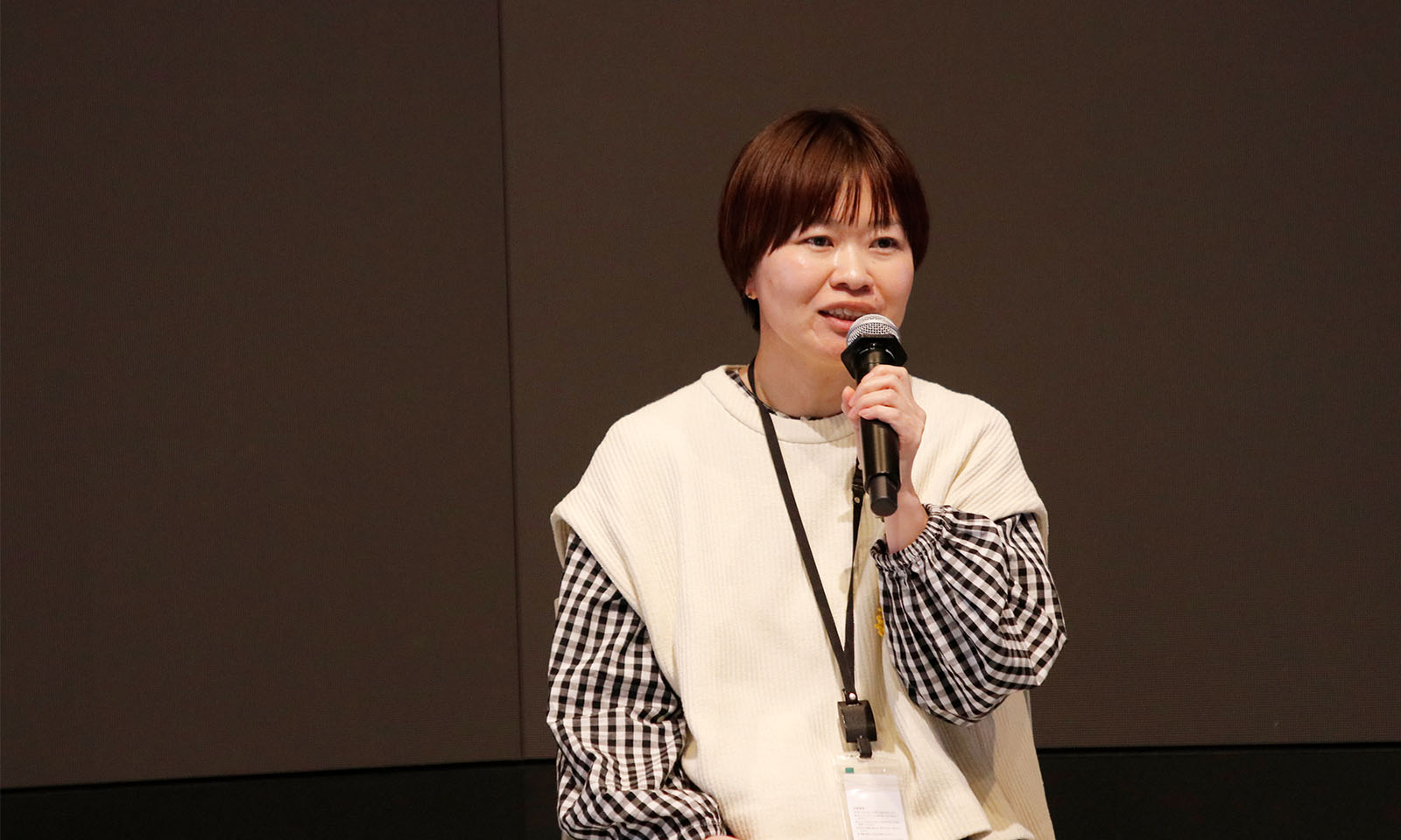 マイクを持ち微笑みながら話す横田さん